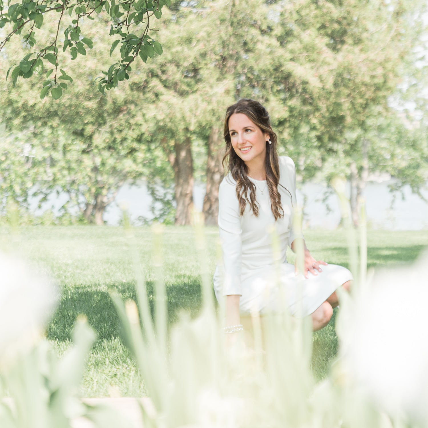 Bride smiling crouching in grass 